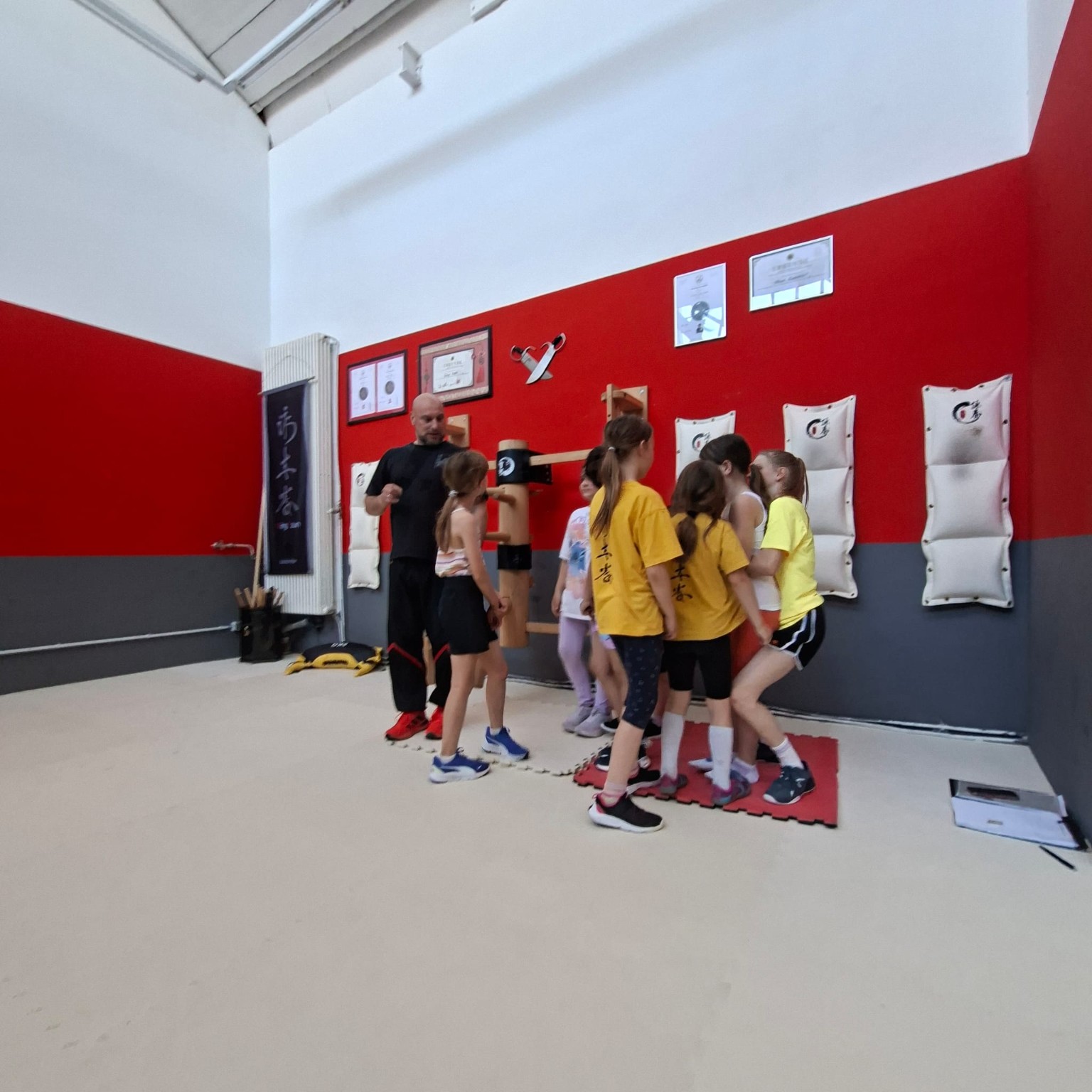 Kindergruppe mit Trainer an der Holzpuppe in der Halle